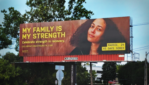 A billboard features a photo of a woman with text that reads "My family is my strength."
